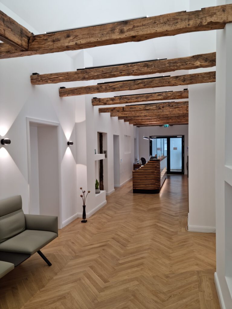 LED-Beleuchtung im Flurbereich einer Allgemeinarztpraxis in Bückeburg mit sichtbaren Holzbalken